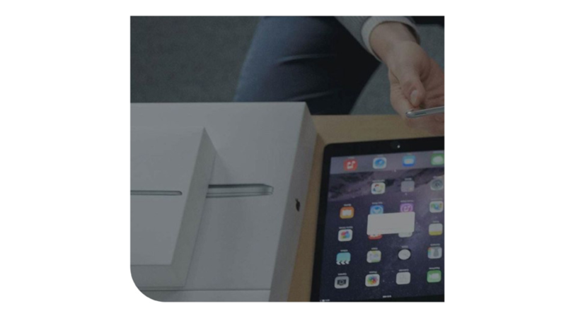 Primer plano de una persona configurando un iPad junto a su caja original sobre una mesa de madera.